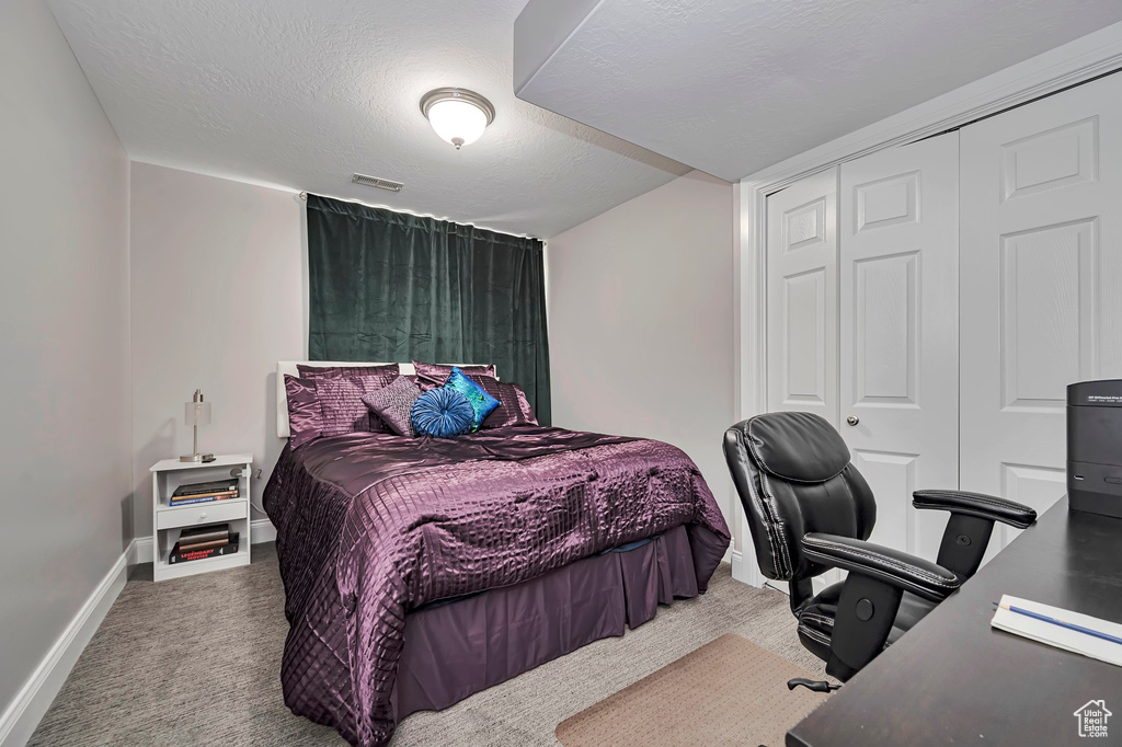 Carpeted bedroom featuring baseboards, a desk, and a closet