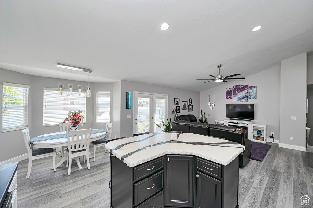 Kitchen featuring light countertops, light wood-style flooring, ceiling fan, a kitchen island, and baseboards