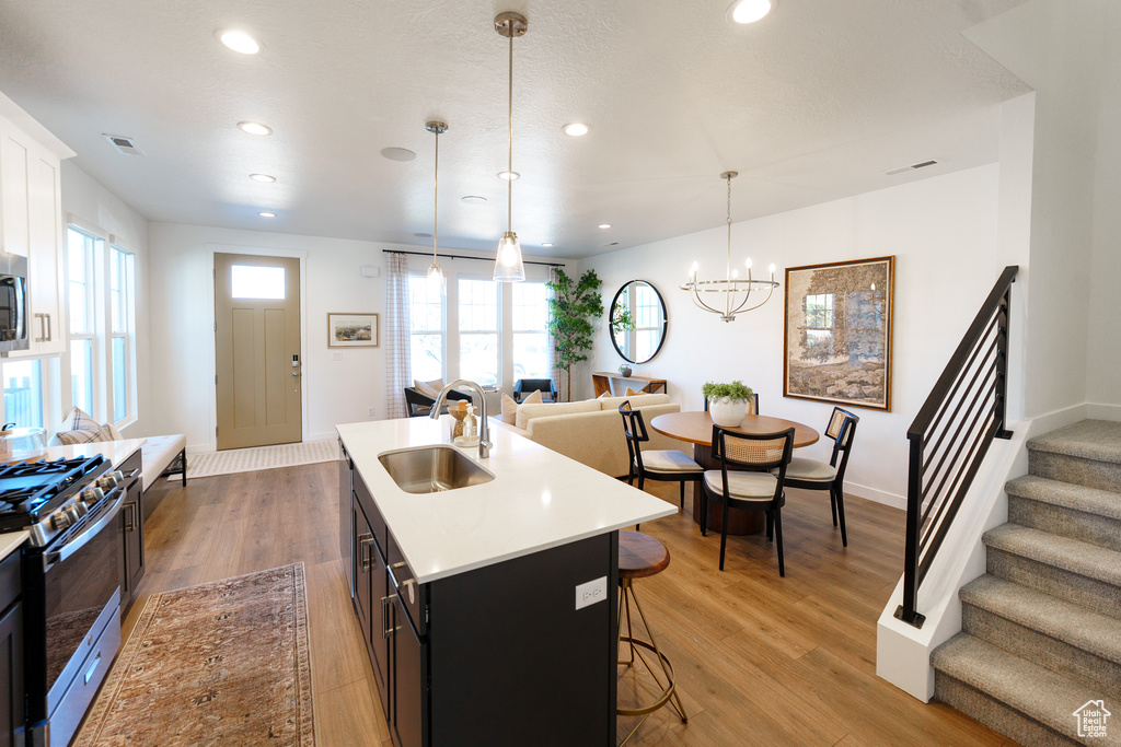 Kitchen with a sink, stainless steel appliances, a breakfast bar area, light countertops, and recessed lighting