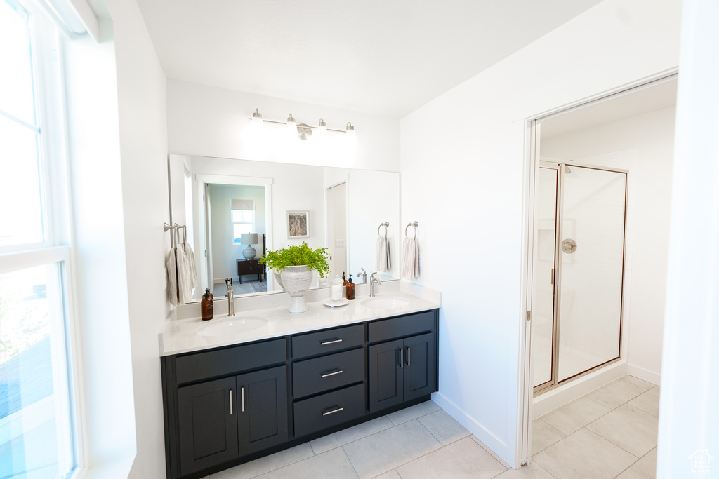 Full bath with tile patterned flooring, double vanity, a shower stall, and baseboards