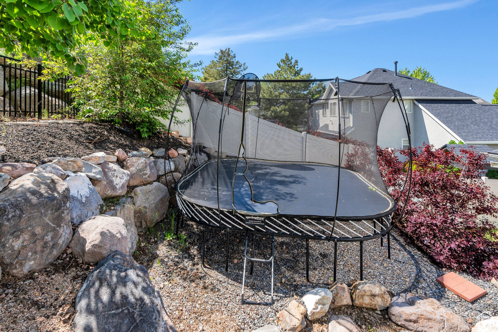 View of yard with a trampoline and fence