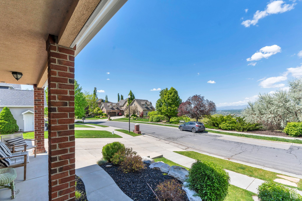 View of asphalt street featuring sidewalks, curbs, and a residential view