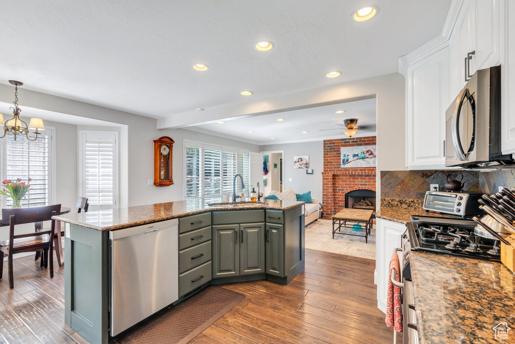 Kitchen featuring stainless steel appliances, a sink, white cabinetry, hardwood / wood-style floors, and ceiling fan