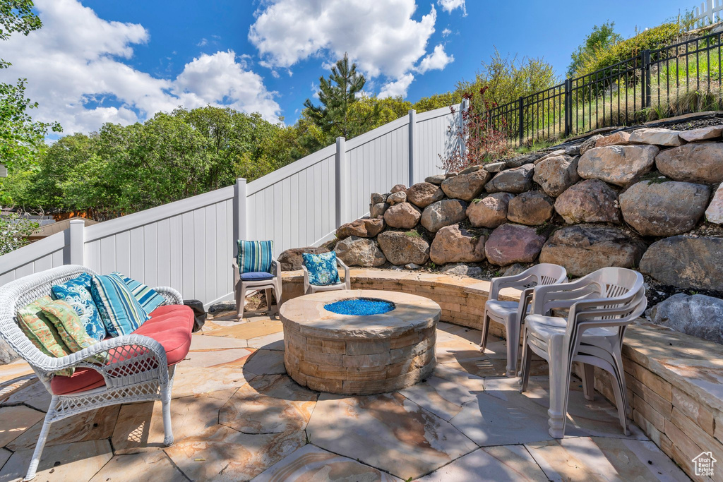 View of patio featuring an outdoor fire pit and a fenced backyard