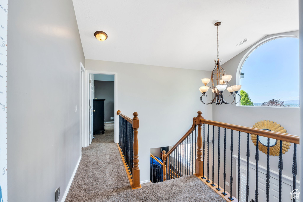 Corridor with an upstairs landing, carpet flooring, lofted ceiling, a chandelier, and baseboards