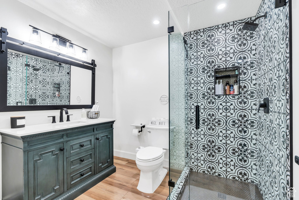 Bathroom featuring wood finished floors, walk in shower, toilet, recessed lighting, and vanity