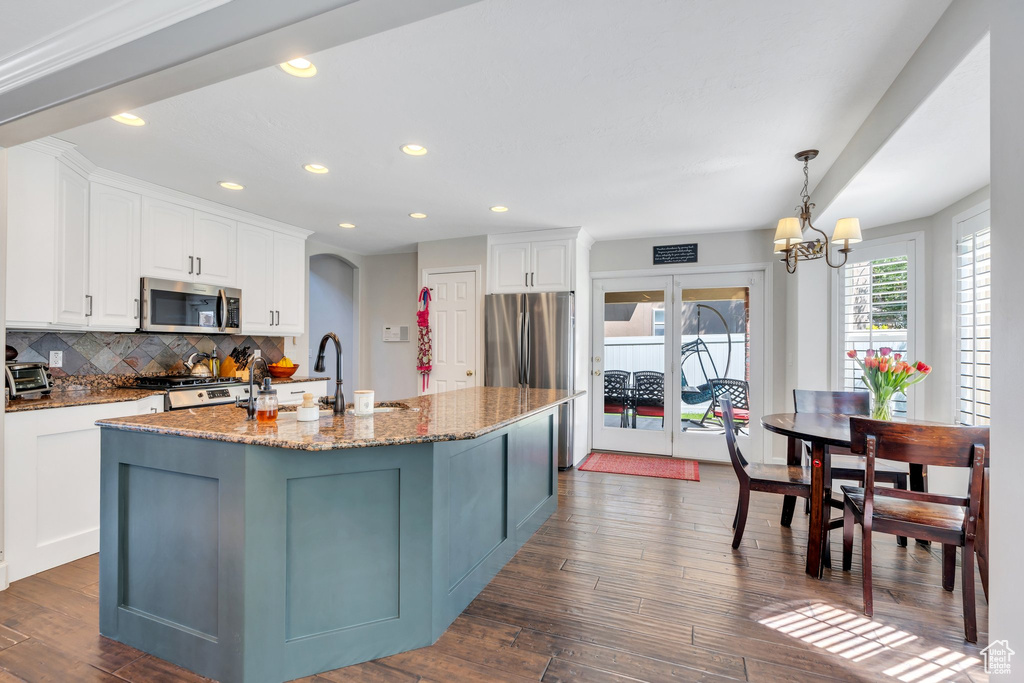 Kitchen featuring appliances with stainless steel finishes, backsplash, white cabinets, dark wood-style floors, and light stone countertops