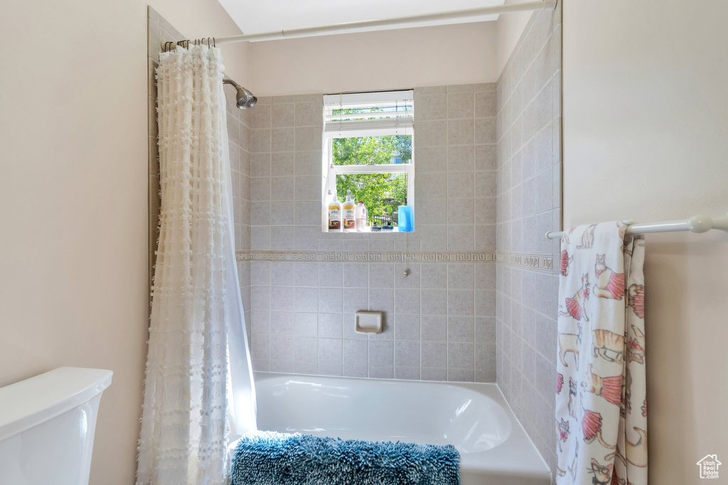 Bathroom with toilet and shower / bathtub combination with curtain