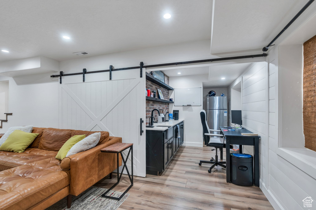 Office space with light wood-style floors, a barn door, recessed lighting, and a sink