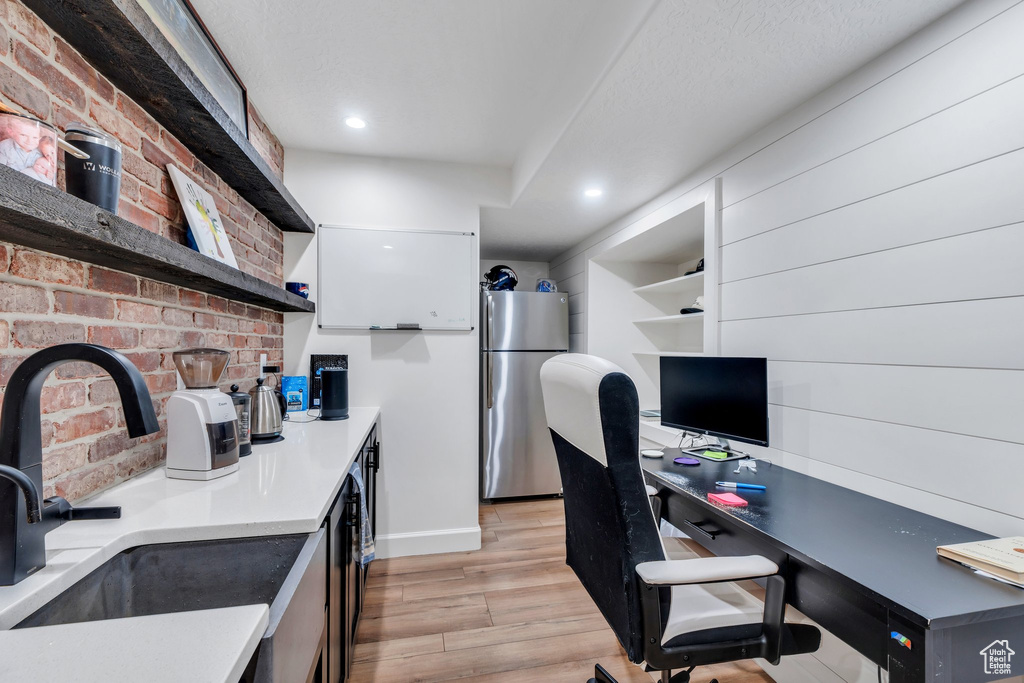 Home office with a sink, light wood-style floors, baseboards, and recessed lighting