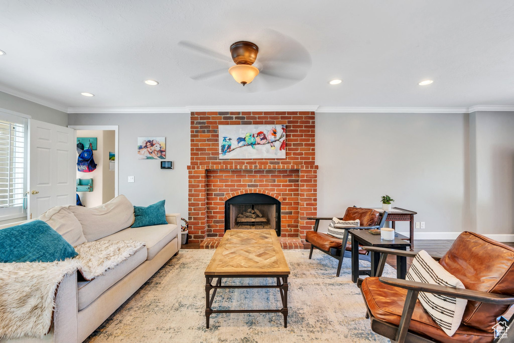 Living area with a brick fireplace, ceiling fan, recessed lighting, and ornamental molding