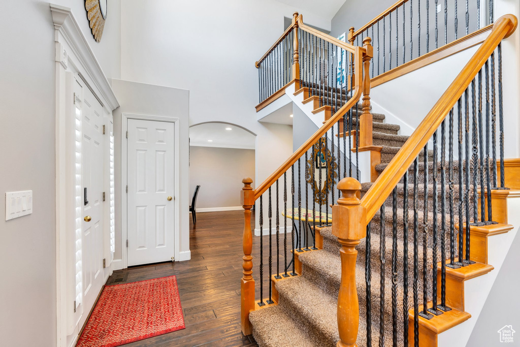 Entrance foyer featuring a high ceiling, wood finished floors, baseboards, arched walkways, and stairs