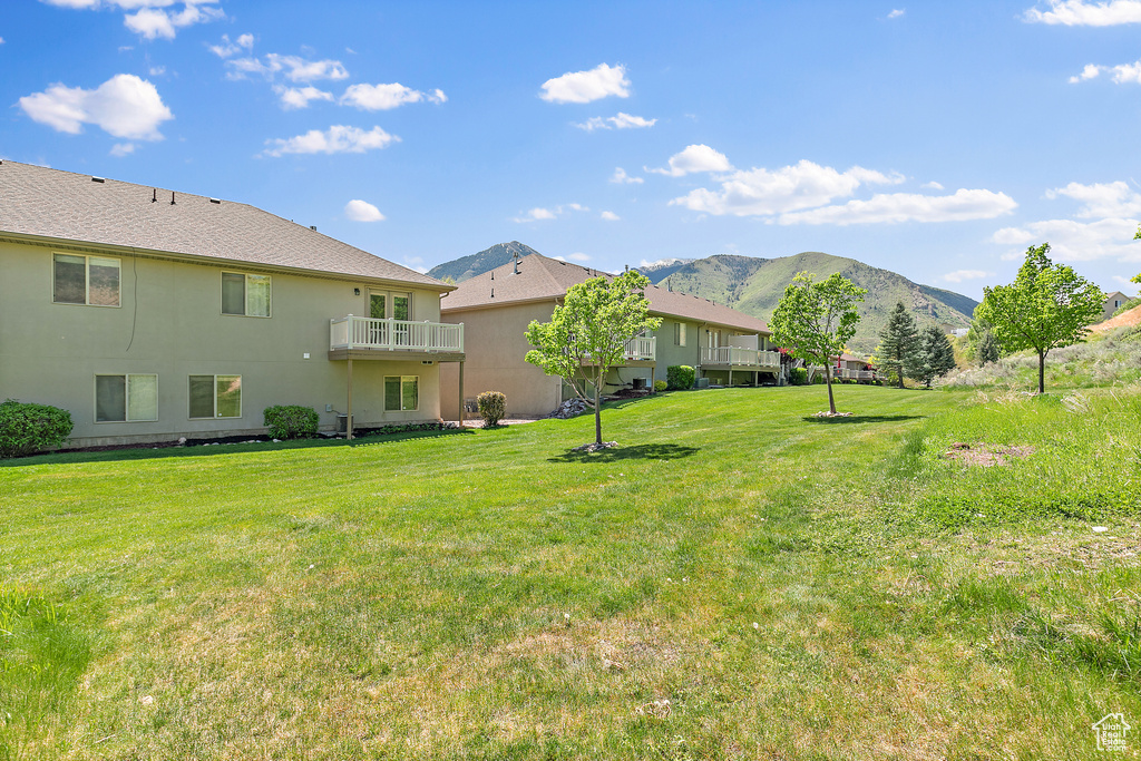 View of grassy yard with a mountain view and a balcony