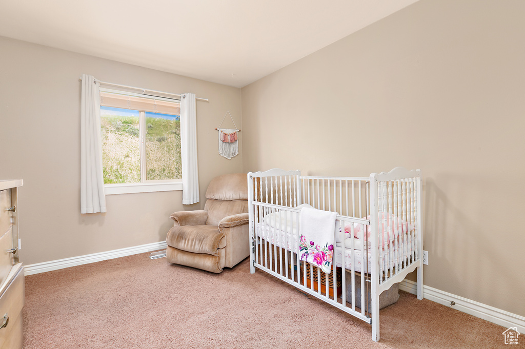 Bedroom featuring carpet flooring, a crib, and baseboards