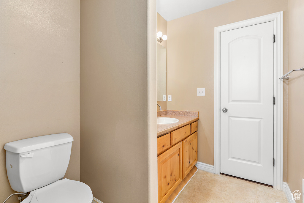 Bathroom with baseboards, vanity, toilet, and tile patterned flooring