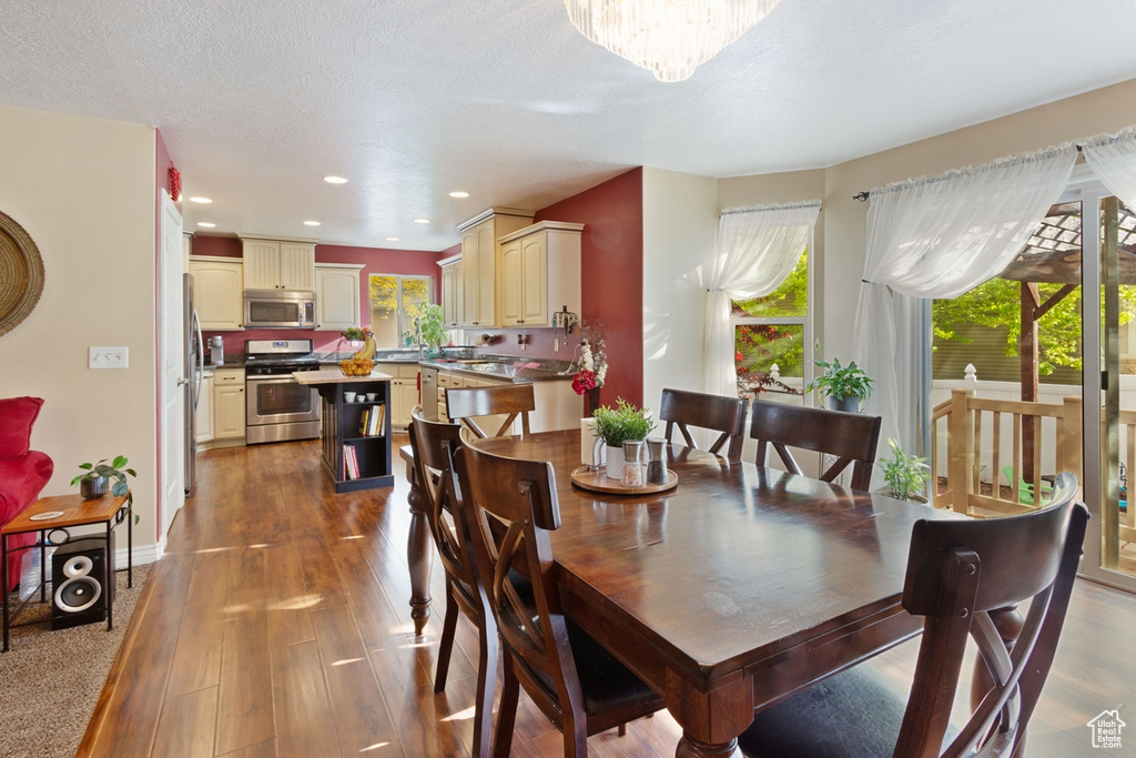 Dining space with wood finished floors, recessed lighting, baseboards, and a chandelier