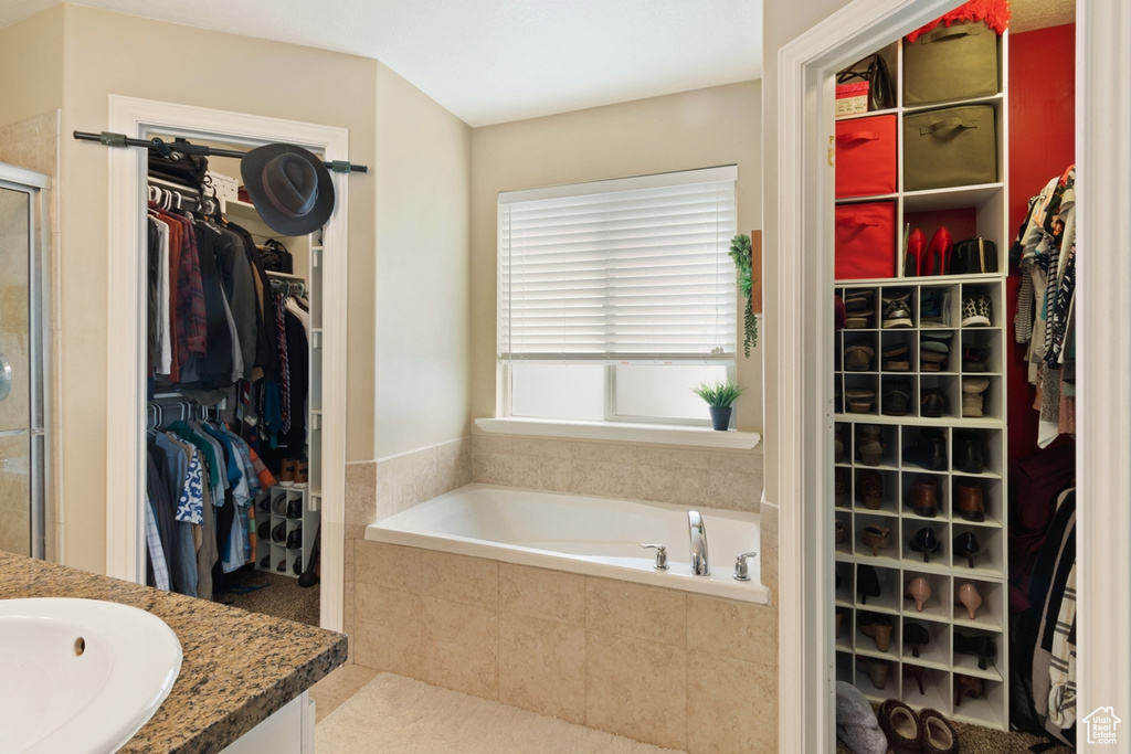 Bathroom featuring a spacious closet, a shower stall, a garden tub, and vanity