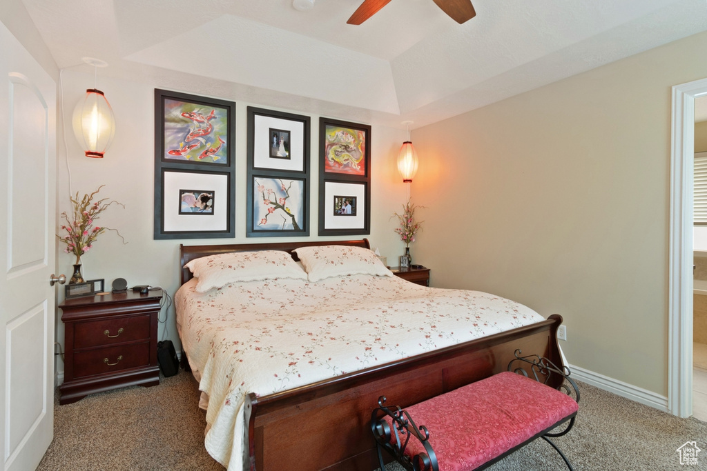 Bedroom featuring carpet floors, a tray ceiling, baseboards, ceiling fan, and connected bathroom