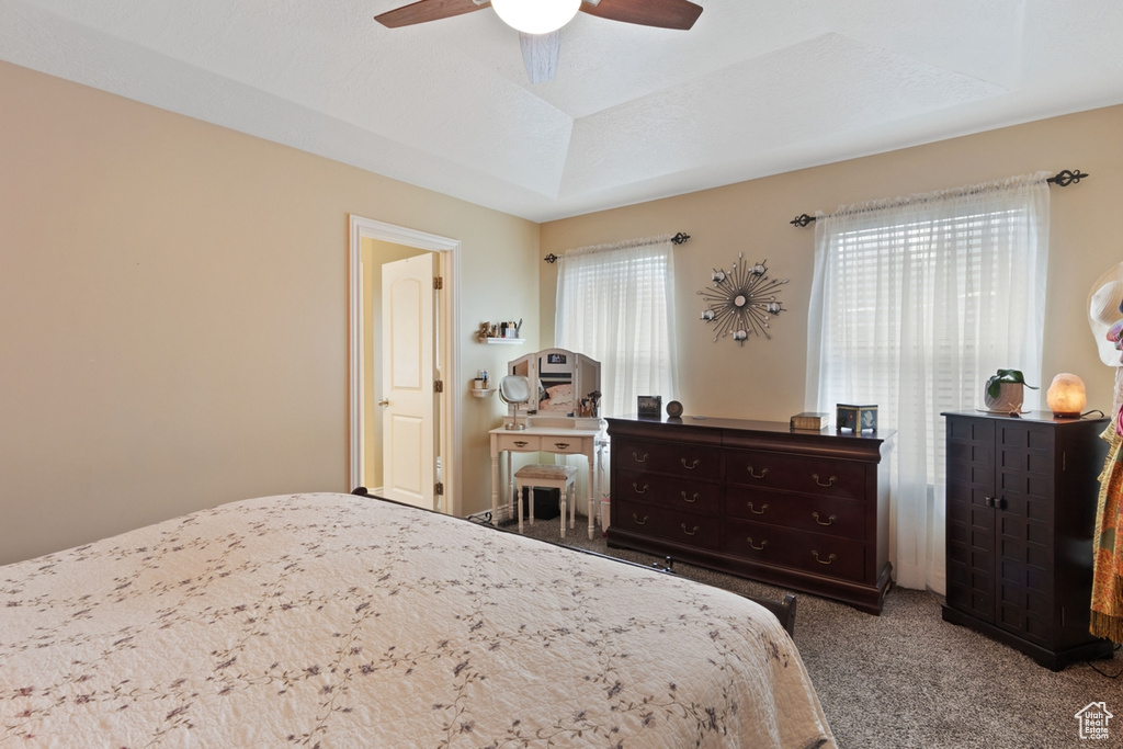 Carpeted bedroom featuring a ceiling fan and a tray ceiling