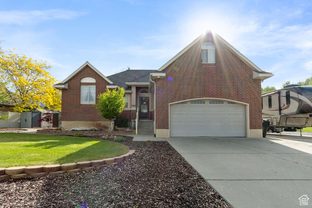 View of front of home with brick siding, concrete driveway, and a front yard