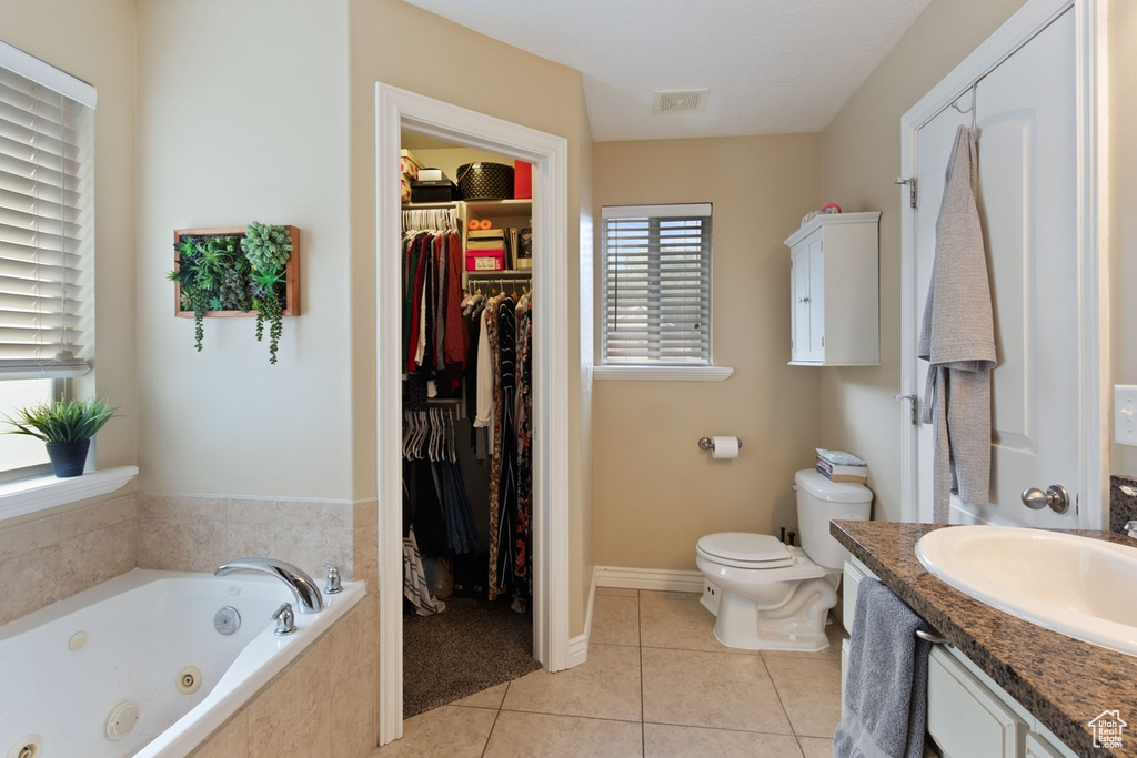 Full bath with a whirlpool tub, tile patterned floors, toilet, a walk in closet, and vanity