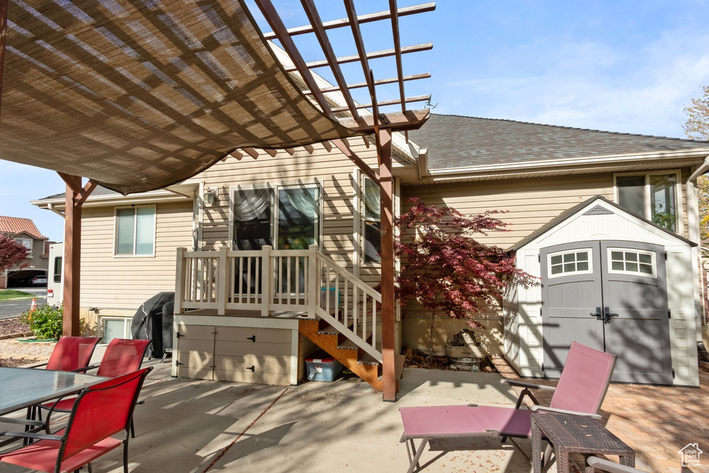 View of patio featuring outdoor dining area, a storage shed, an outbuilding, and a pergola
