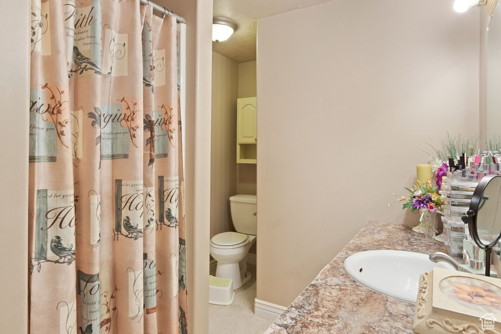 Full bathroom with toilet, vanity, tile patterned floors, and a shower with shower curtain