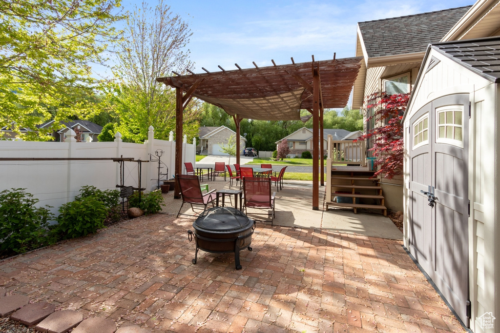 View of patio featuring an outdoor fire pit, fence, a pergola, and outdoor dining space