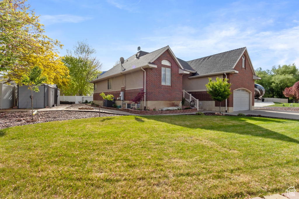 View of side of home featuring brick siding, an attached garage, a shed, an outbuilding, and roof with shingles