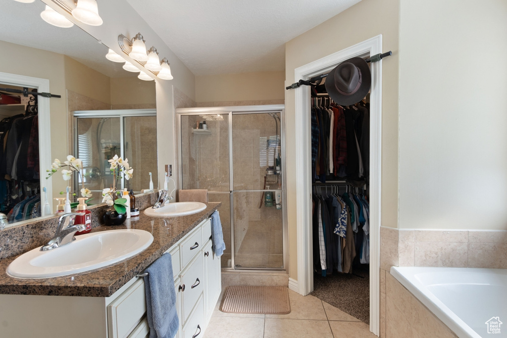 Bathroom with tile patterned floors, a shower stall, double vanity, a spacious closet, and a relaxing tiled tub