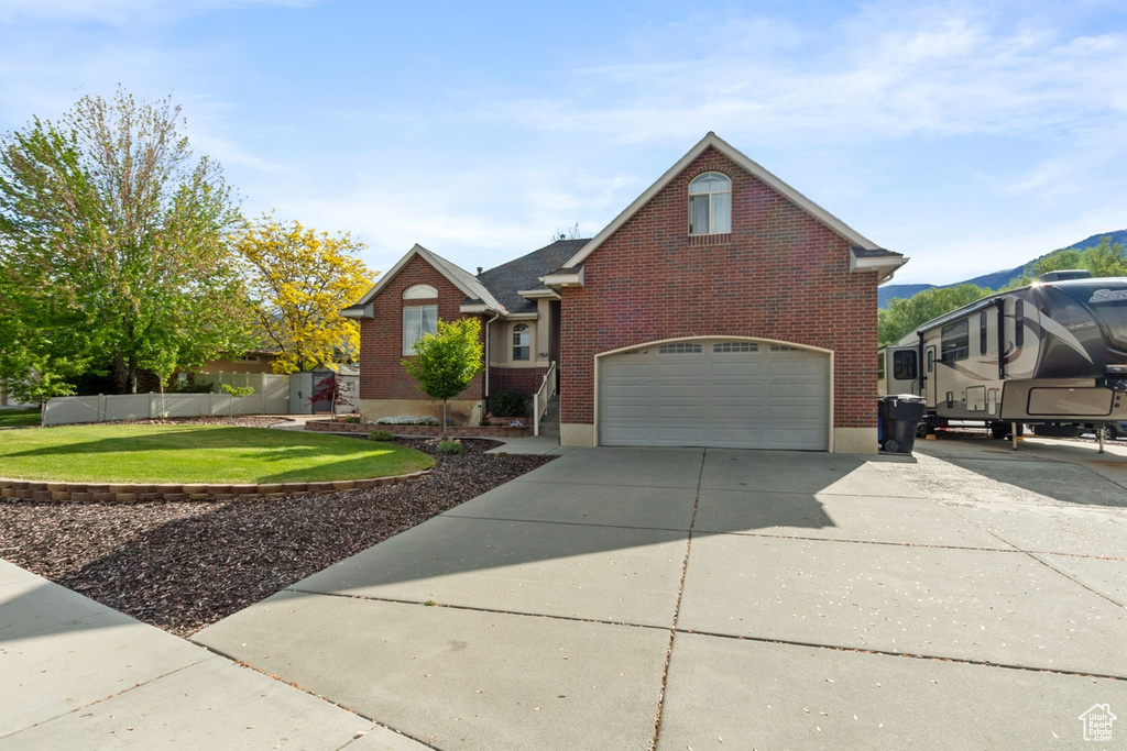 Traditional-style house with a garage, brick siding, concrete driveway, and a mountain view