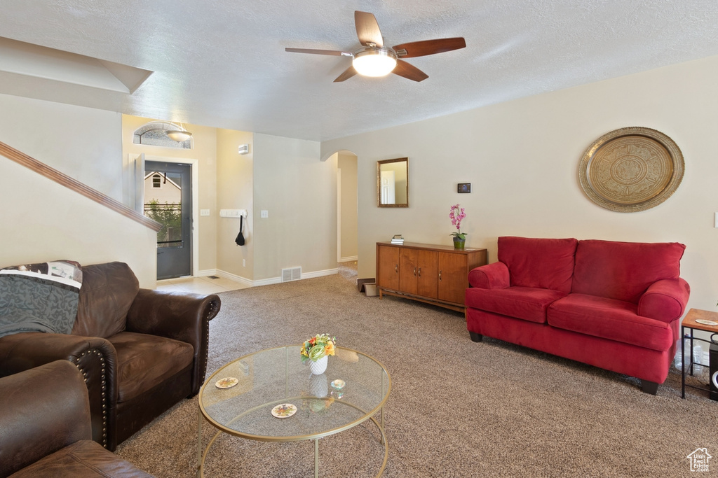 Living area featuring arched walkways, carpet flooring, a ceiling fan, and baseboards