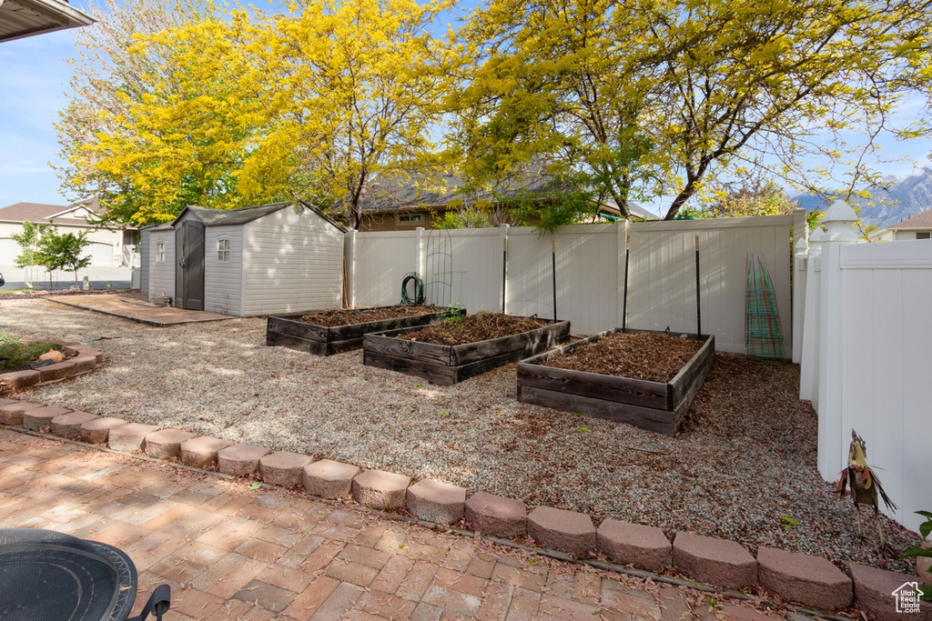 Fenced backyard with a vegetable garden, a storage unit, and an outbuilding