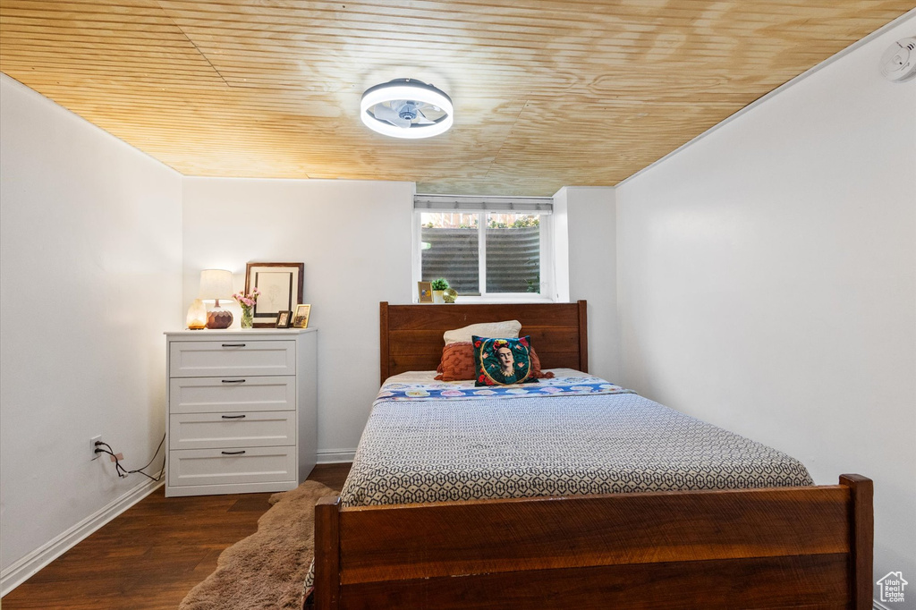 Bedroom with baseboards, wooden ceiling, and dark wood-style floors