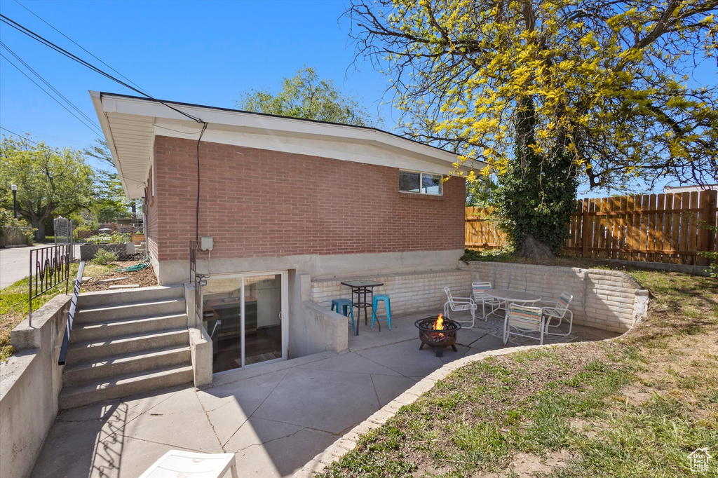 Exterior space with fence, a patio, a fire pit, and brick siding