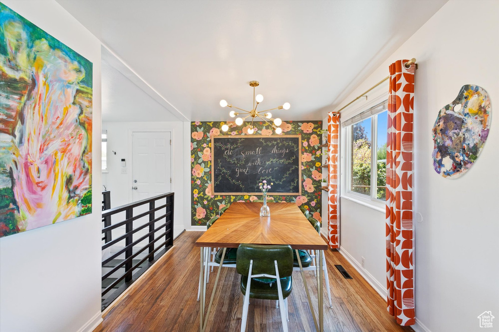 Dining space with visible vents, baseboards, a notable chandelier, and wood finished floors