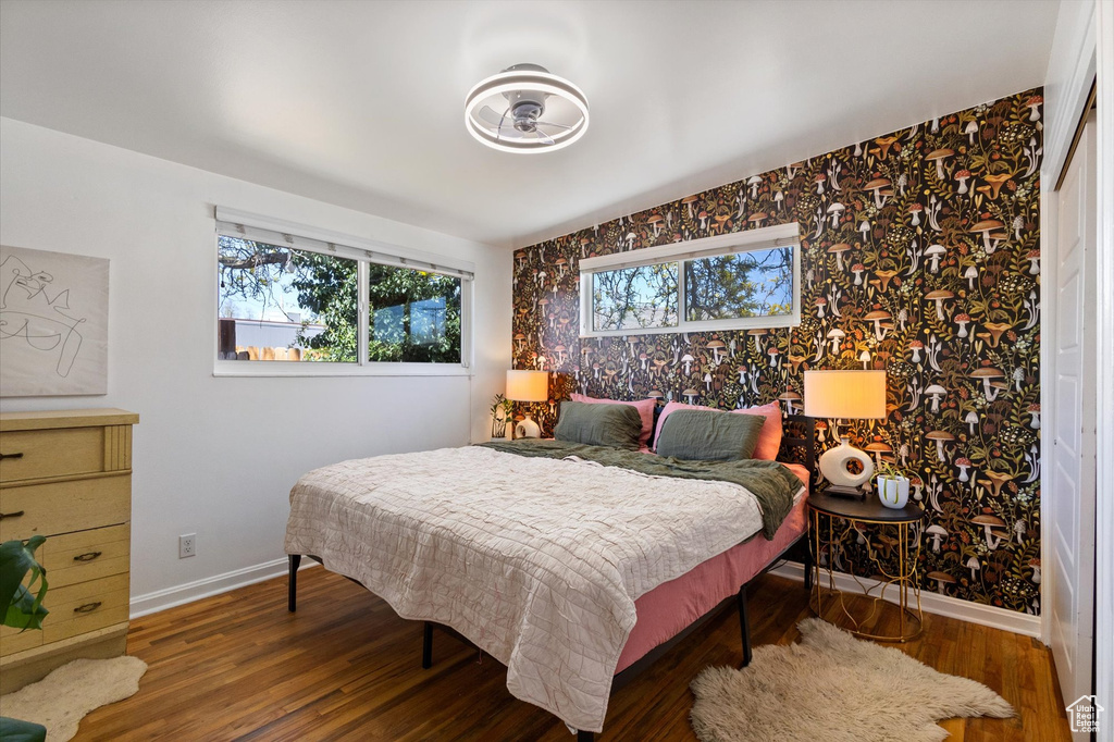 Bedroom with wood finished floors, baseboards, and multiple windows