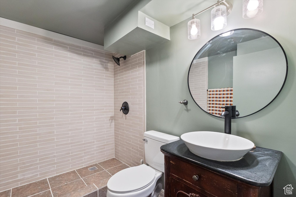 Full bathroom featuring toilet, tiled shower, and vanity