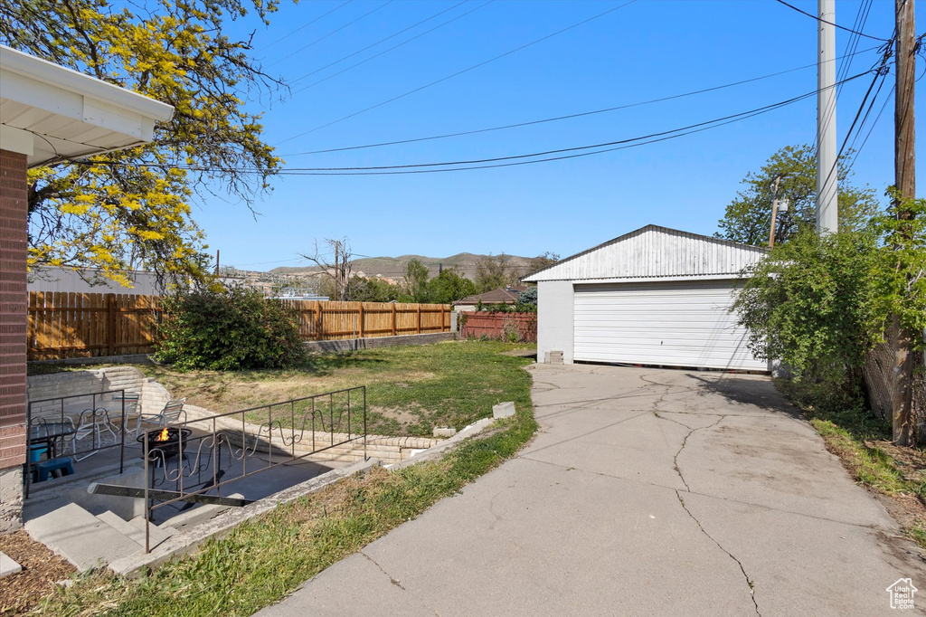 View of yard featuring a mountain view, an outdoor structure, fence, and a detached garage