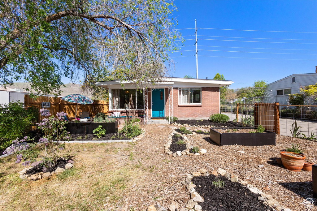 View of front of property with brick siding, a garden, and fence