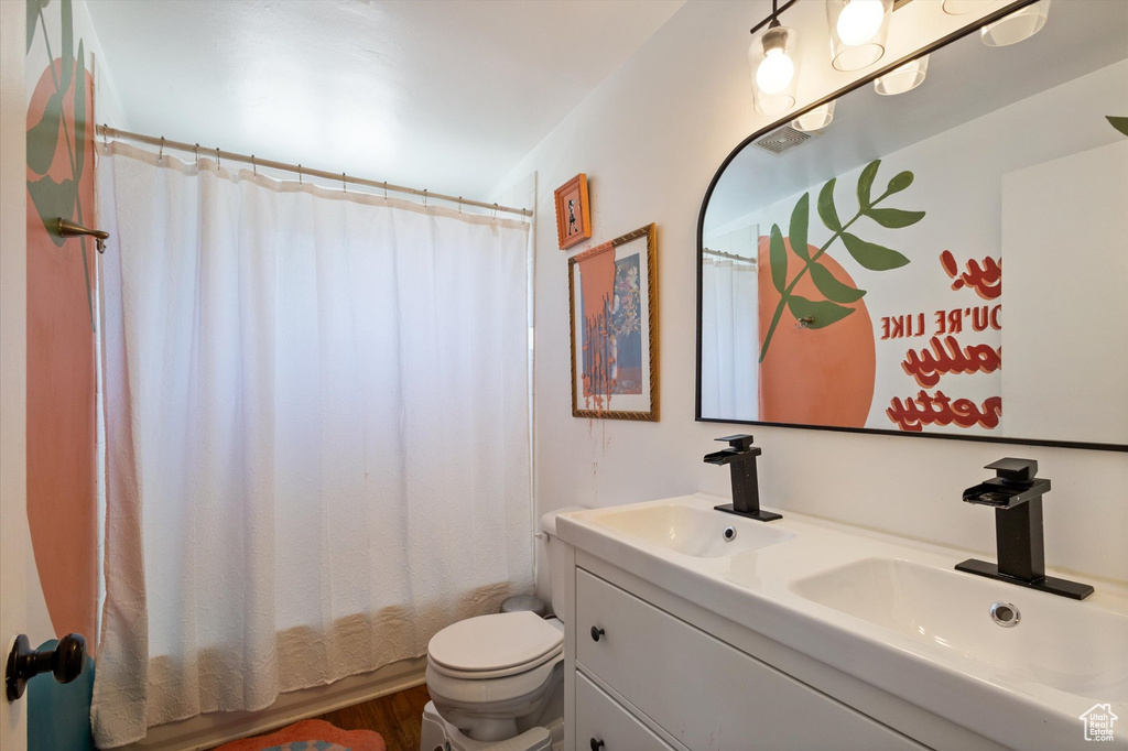 Bathroom featuring toilet, double vanity, a sink, and shower / bathtub combination with curtain