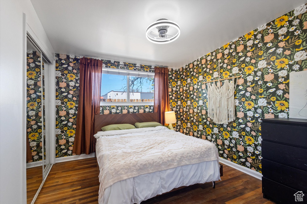 Bedroom with baseboards, wallpapered walls, and wood finished floors