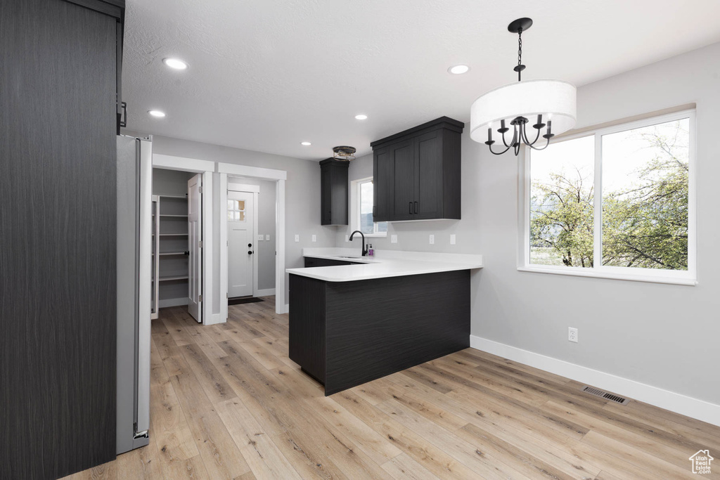 Kitchen with a peninsula, a sink, light countertops, baseboards, and recessed lighting