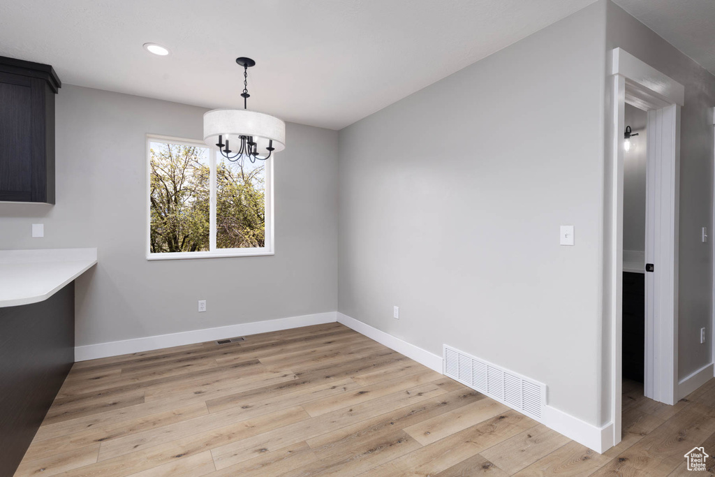 Unfurnished dining area featuring light wood finished floors, a chandelier, baseboards, and recessed lighting