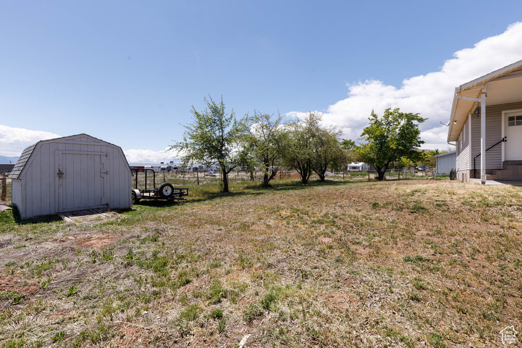 View of yard featuring a storage shed, an outbuilding, and fence