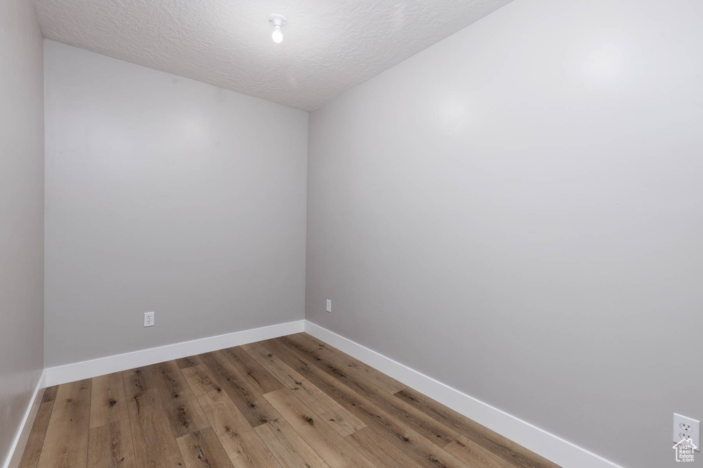 Unfurnished room with baseboards, wood finished floors, and a textured ceiling