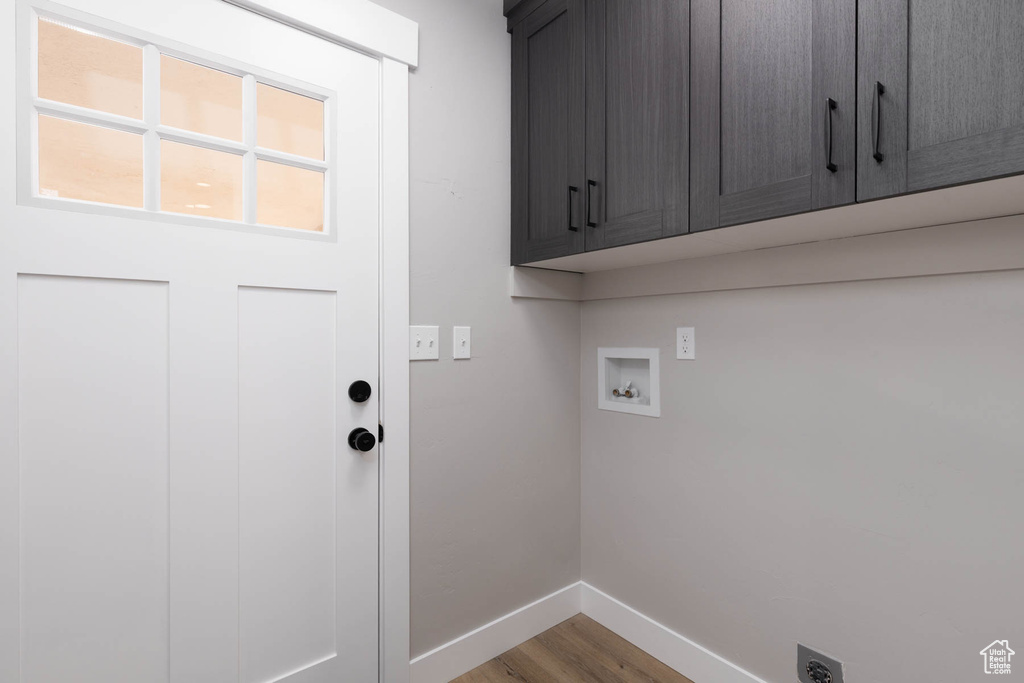 Washroom featuring cabinet space, hookup for an electric dryer, baseboards, wood finished floors, and hookup for a washing machine