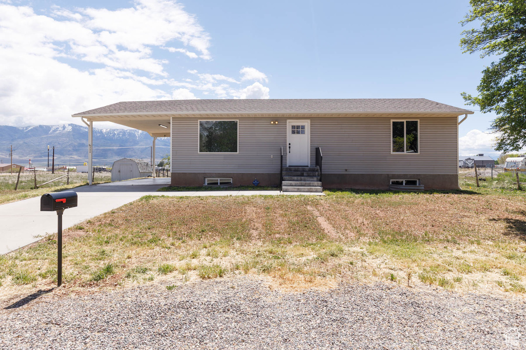 View of front of property with driveway, entry steps, a carport, a mountain view, and an outdoor structure
