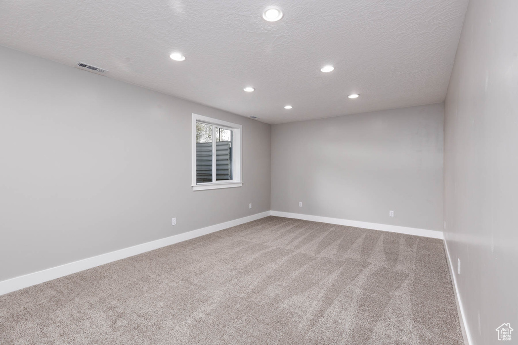 Carpeted spare room with recessed lighting, a textured ceiling, and baseboards