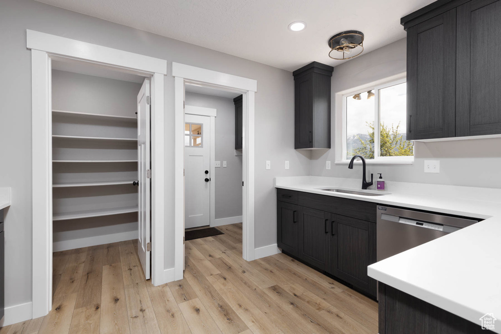 Kitchen with a sink, light countertops, light wood-type flooring, and recessed lighting